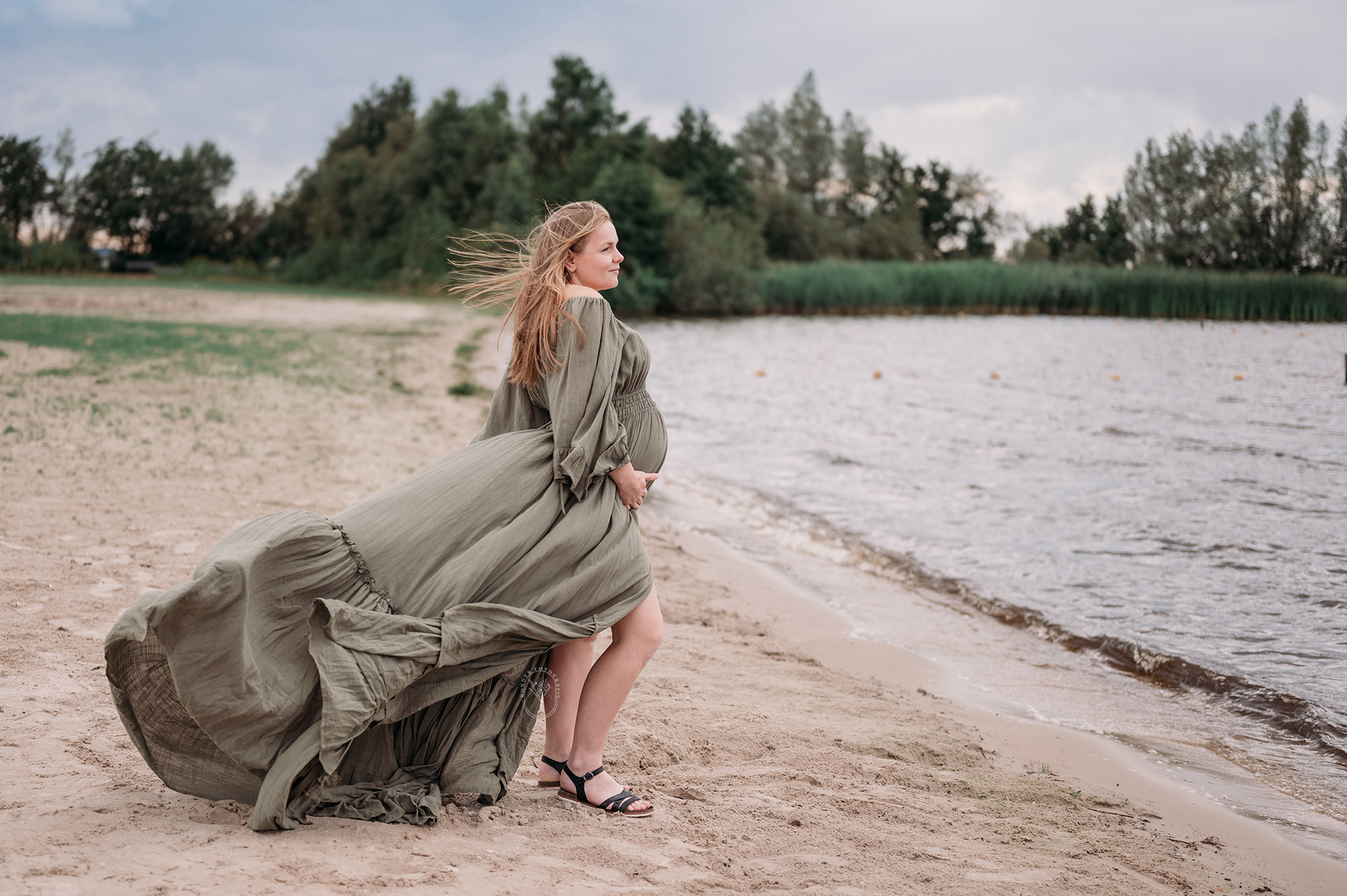 Zwangere moeder in vloeiende jurk tijdens strandshoot in Flevoland