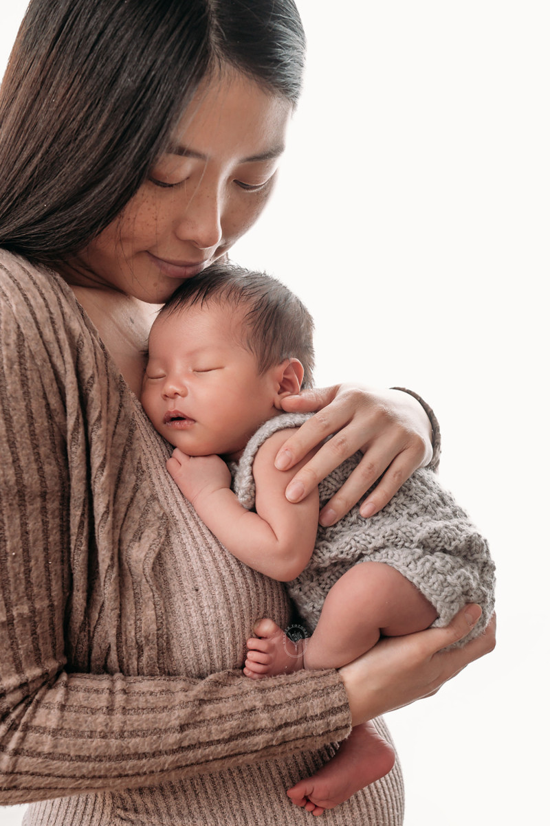 Moeder met pasgeboren baby tijdens newborn shoot aan huis in Steenwijk