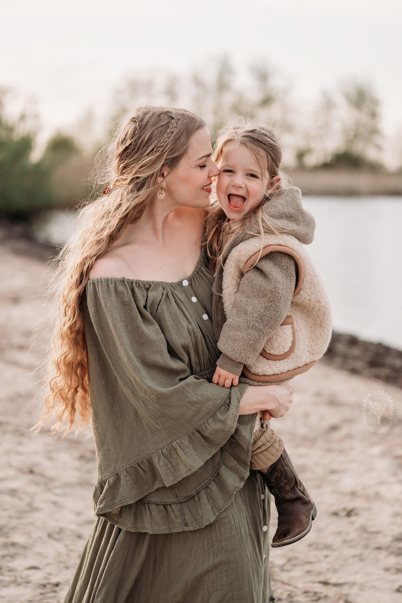 Liefdevol moment tussen ouders en kinderen tijdens fotoshoot in de natuur